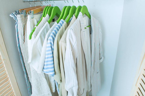 zomergarderobe met linnen kleding op groene hangers - Foto, afbeelding