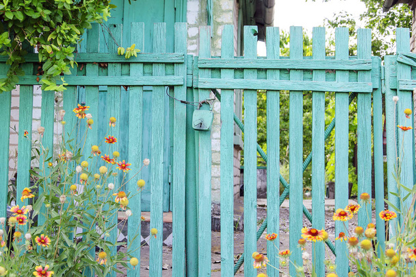 ロック付き緑色の木製フェンス。家の前の門、花 - 写真・画像