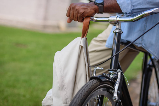 cropped view of african american man standing near bicycle with backpack - Zdjęcie, obraz