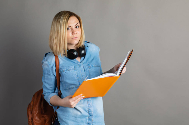 bir sırt çantası ve textboo ile güzel bir kız öğrencinin portresi - Fotoğraf, Görsel