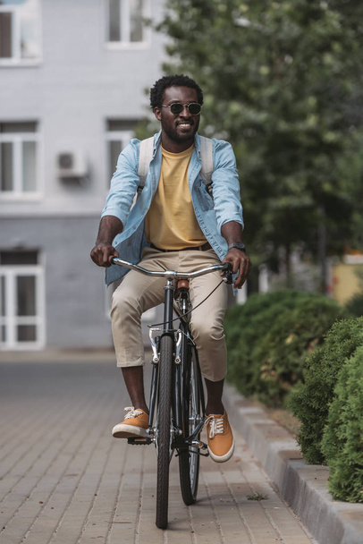 cheerful, stylish african american man smiling while riding bicycle - Fotoğraf, Görsel