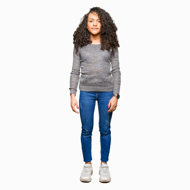 Young beautiful woman with curly hair wearing grey sweater Relaxed with serious expression on face. Simple and natural looking at the camera. - Foto, Imagen