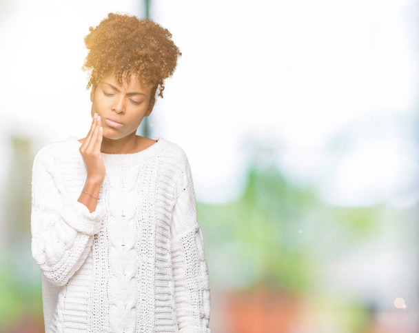 Bella giovane donna afroamericana che indossa maglione invernale su sfondo isolato toccando bocca con mano con espressione dolorosa a causa di mal di denti o malattia dentale sui denti. Concetto di dentista
. - Foto, immagini