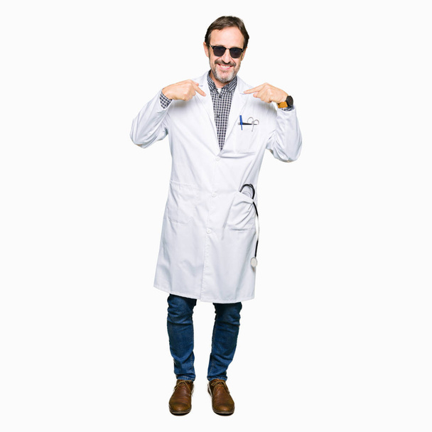 Handsome middle age doctor man wearing sunglasses looking confident with smile on face, pointing oneself with fingers proud and happy. - Photo, image