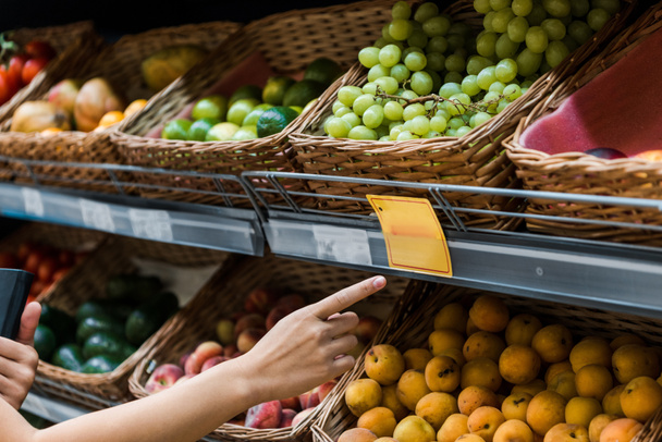 foco seletivo da mulher apontando com o dedo para frutas no supermercado
  - Foto, Imagem