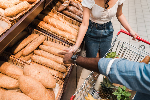 overhead view of african american man pointing with finger at bread in supermarket  - 写真・画像