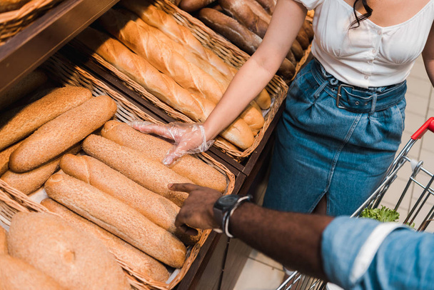 vista recortada del hombre afroamericano señalando con el dedo el pan en el supermercado
  - Foto, Imagen