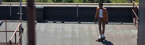 панорамний знімок афроамериканського бізнесмена, який верхи на самотній дошці на даху
 - Фото, зображення