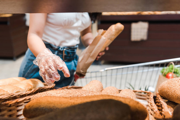 cropped view of young woman in glove near bread in supermarket  - Fotografie, Obrázek