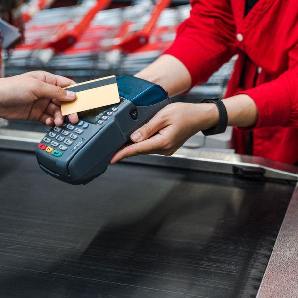 vista ritagliata di uomo che paga con carta di credito vicino alla donna nel supermercato
  - Foto, immagini