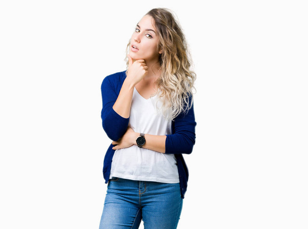 Beautiful young blonde woman over isolated background with hand on chin thinking about question, pensive expression. Smiling with thoughtful face. Doubt concept. - Photo, image