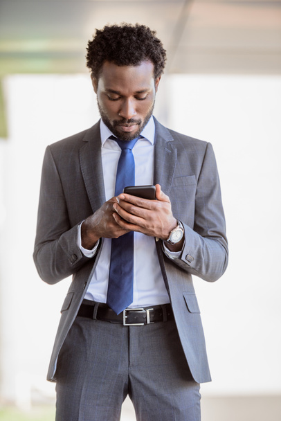 handsome african american businessman in suit using smartphone on street - Photo, image