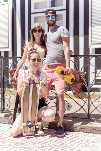 Three young active friends enjoying a summer sunny day skateboar - Φωτογραφία, εικόνα