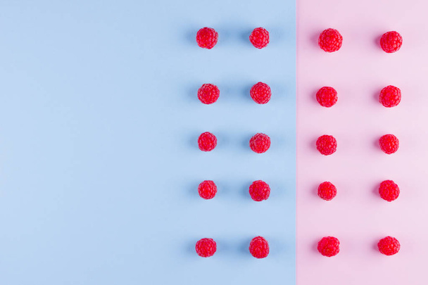 Pattern of raspberries on pink blue background. Colorful diet and healthy food concept. Background of raspberries. Top view. Flat lay. Copy space - Φωτογραφία, εικόνα