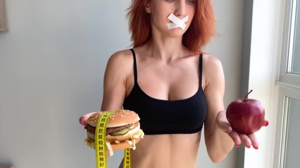Pojęcie diety, piękna młoda kobieta wybierając między zdrowej żywności i fast foodów - Materiał filmowy, wideo
