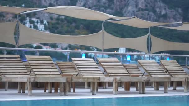 Free wooden chaise lounges near the pool among mountain landscape, slow motion - Footage, Video