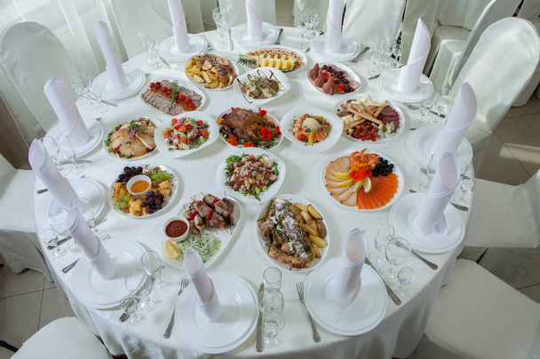 Mooie feestelijke tafel geserveerd voor bruiloft viering diner thuis of restaurant interieur. Tafel vol eten in een restaurant. Volledige ronde tafel. - Foto, afbeelding