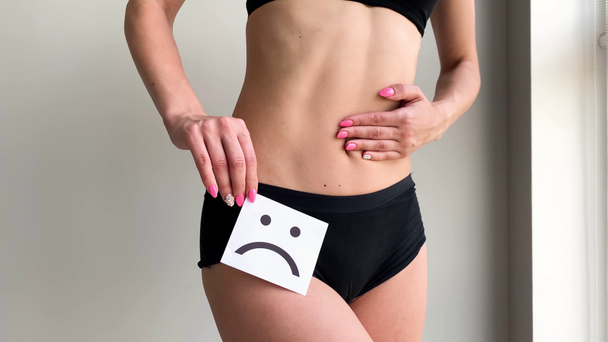 Υγεία της γυναίκας. Γυναικείου σώματος κρατώντας θλιβερό χαμόγελο κάρτα κοντά στο στομάχι - Πλάνα, βίντεο