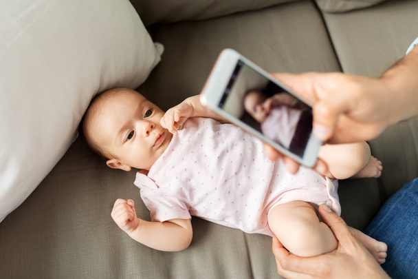 father with smartphone taking picture baby at home - Фото, изображение