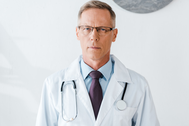 handsome doctor in glasses and white coat looking at camera  - 写真・画像