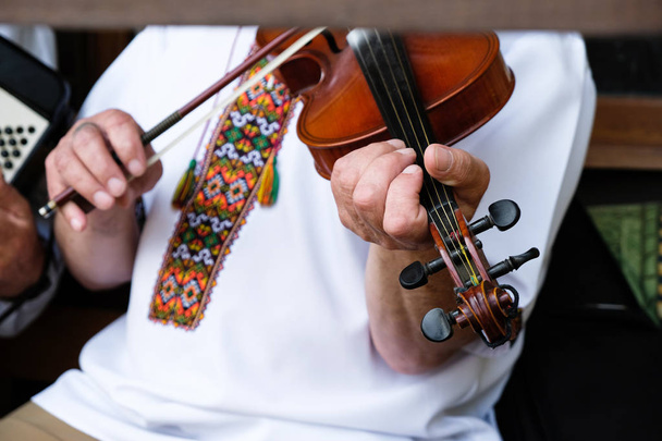 Fragmento do violino e as mãos do homem. O homem tem uma camisa branca bordada. Folclore ucraniano
. - Foto, Imagem
