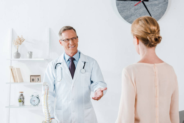 selective focus of happy doctor gesturing while looking at woman  - Foto, immagini