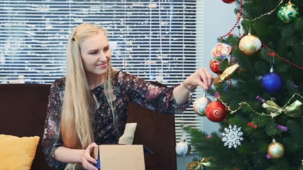 Front view of pretty woman hanging balls on Christmas tree - Footage, Video