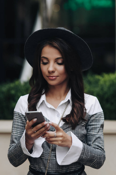 Vertical portrait of beautiful brunette girl typing message on h - Фото, изображение