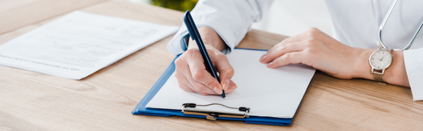 panoramic shot of doctor writing diagnosis on wooden table  - Photo, Image