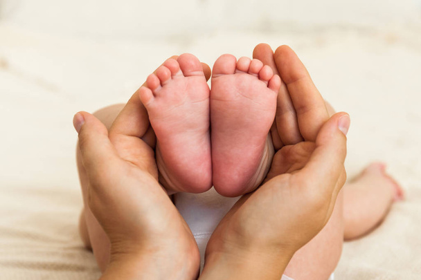 De voeten van de baby in handen van de moeder. Moeder en haar kind. - Foto, afbeelding