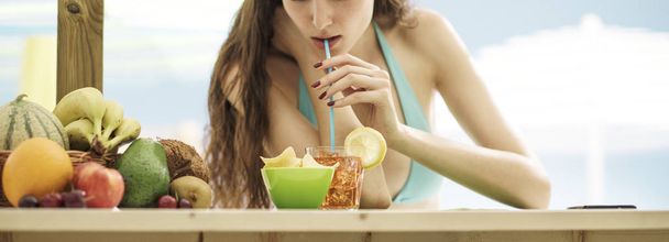Attractive young woman having a cocktail at the beach - Foto, Bild