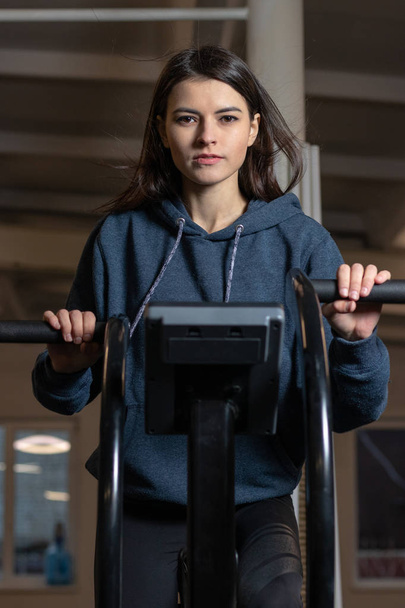 The girl is engaged on a crossfit exercise bike in the gym - Foto, immagini