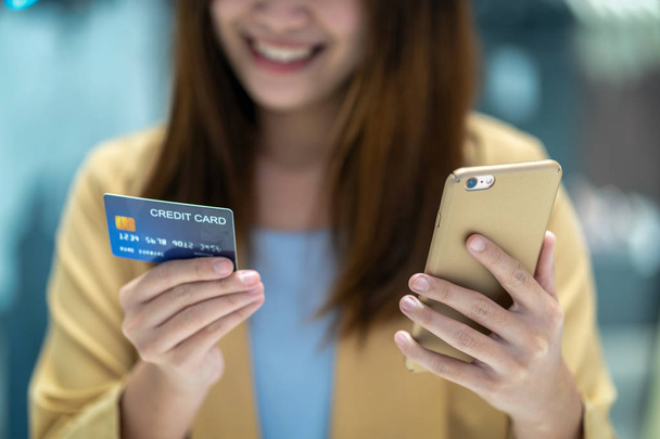 クローズ アップ アジアの女性服ショップ ストアの背景、技術お金財布とオンライン決済コンセプト、クレジット カード モックアップでデパートのオンライン ショッピングのための携帯電話でクレジット カードを使用して - 写真・画像