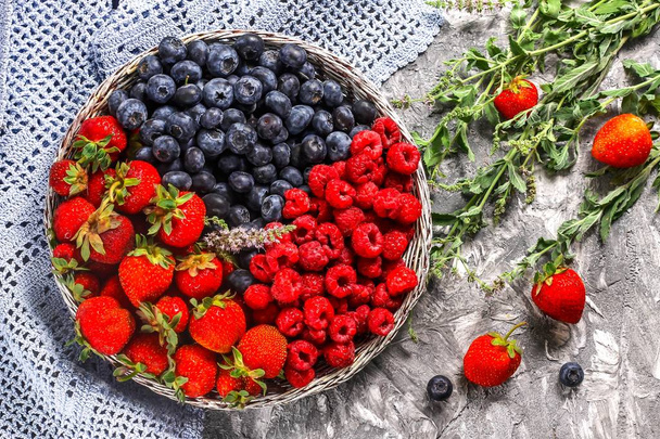 Корзина со свежими ягодами на бетонном фоне - летний сбор ягод
.  - Фото, изображение