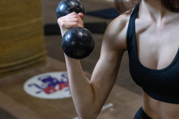 The girl is engaged with dumbbells in the gym - Foto, afbeelding