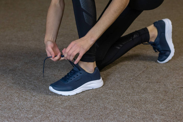 Girl tying shoelaces on sneakers in the gym - Fotografie, Obrázek