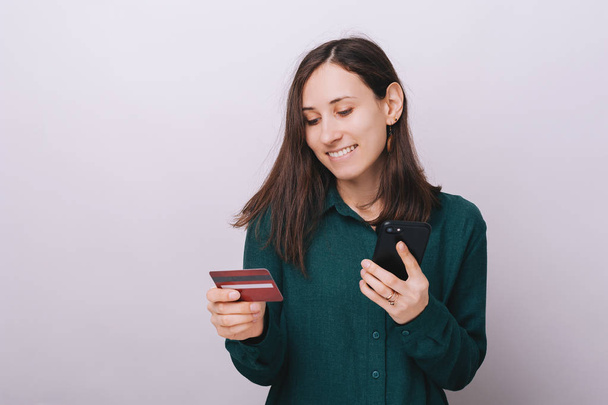 Foto einer jungen Frau, die ihre Kreditkarte benutzt, um online einzukaufen, vor isoliertem Hintergrund  - Foto, Bild
