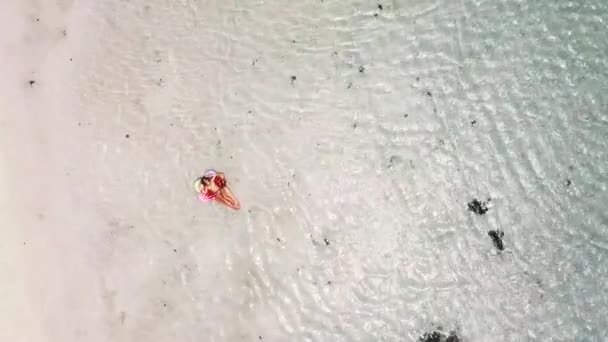 вид с воздуха на молодую женщину, принимающую солнечную ванну, расслабляющуюся на надувном матраце lilo в голубой тропической океанской лагуне
  - Кадры, видео