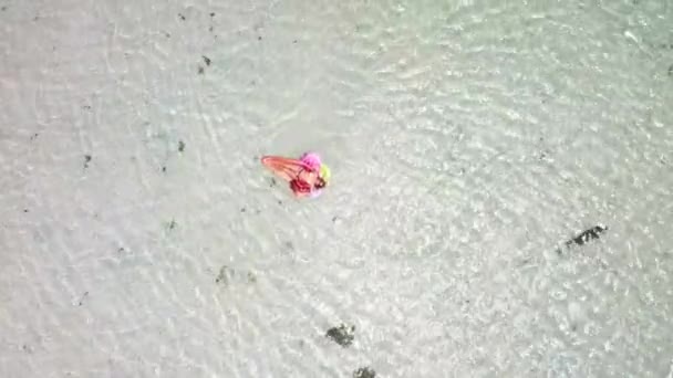 vista aérea da mulher nova que tem o banho de sol que relaxa no colchão inflável do lilo na lagoa tropical azul do oceano
  - Filmagem, Vídeo