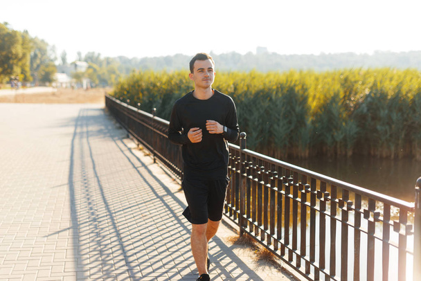 Conceito de esporte, um jovem homem, vestindo roupas esportivas, manhã correndo no parque
 - Foto, Imagem