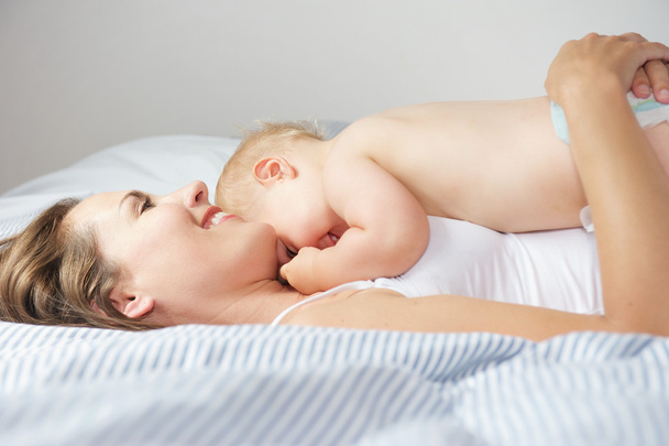 Baby hugging mother in bed - Фото, зображення