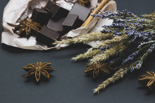chocolate natural com flores de lavanda canela e anis estrelado em um fundo escuro
 - Foto, Imagem