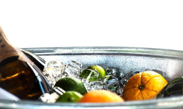 Inside the ice bucket with bottle of vine, limes and oranges, wh - Photo, Image