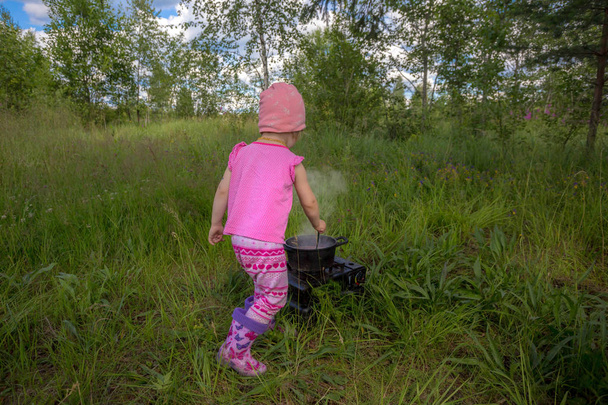 Kenttäkeittiö. lapsi kokkaa tattaripuuroa kaasuliedellä
 - Valokuva, kuva