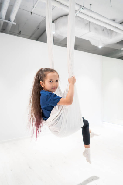 portrait of a beautiful young girl engaged in fly yoga on canvases. - 写真・画像
