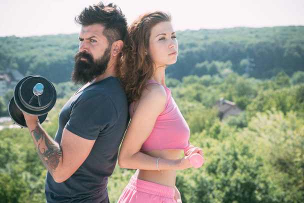 Achieving physical fitness. Fit woman and hipster doing fitness activity. Athletic woman and strong bearded man keeping fitness with dumbbell workout. Sexy couple of athletes improving their fitness - 写真・画像