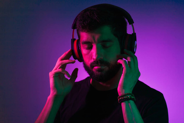 Neon light portrait of bearded man in headphones. Listening to music - Фото, изображение