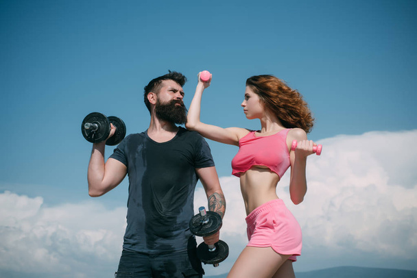 bearded man and woman with fit belly. healthy lifestyle. dieting. freedom. dumbbell lifting. sport and fitness. sporty couple training outdoor. perfect body muscle. summer activity. barbell equipment - Fotó, kép