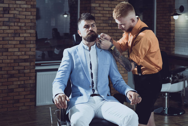Hair Stylist and Barber. Hair salon and barber vintage. Brutal guy in modern Barber Shop. Trims. Great time at barbershop. Barber making haircut of attractive bearded man in barbershop. - Foto, afbeelding