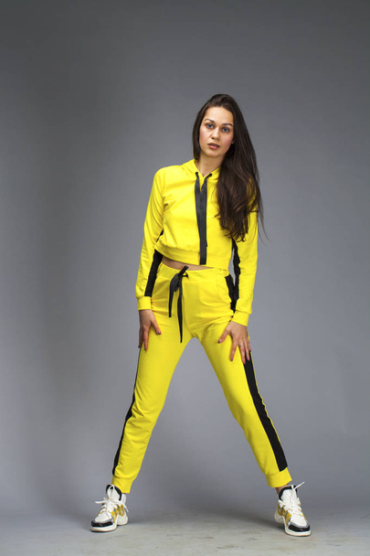 Portrait of a young beautiful brunette woman in yellow tracksuit - Fotografie, Obrázek